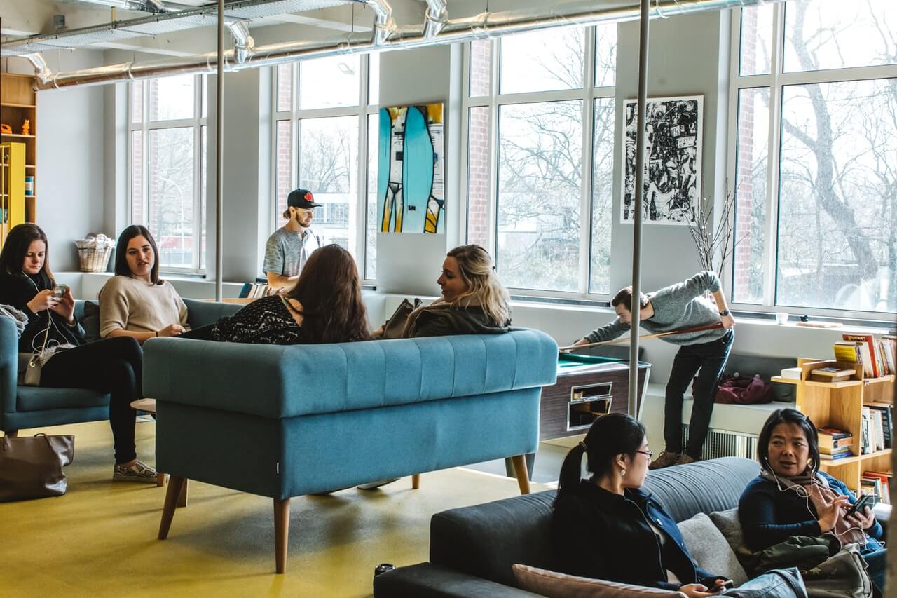people sitting in an open room with couches and a pool table