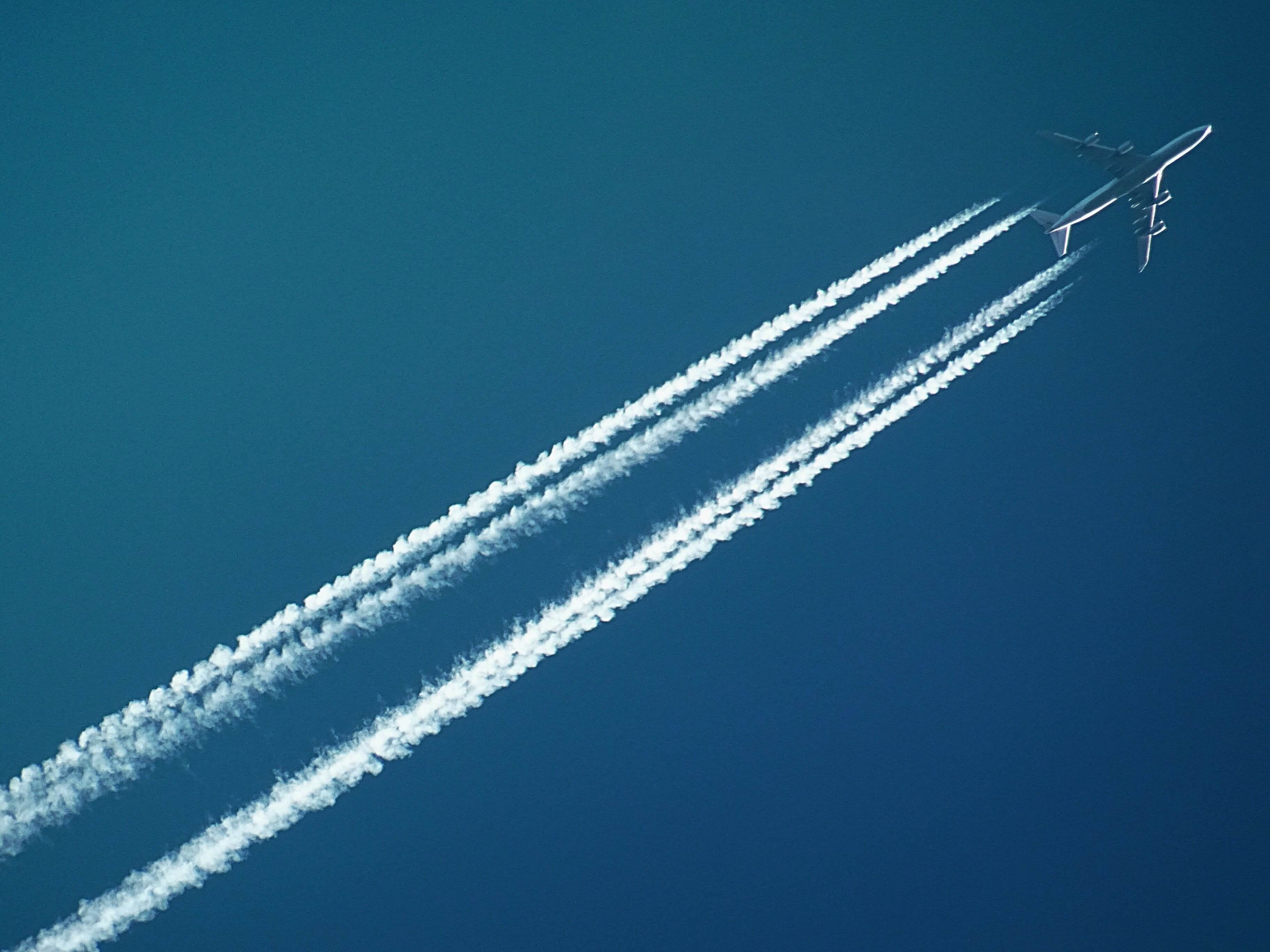 airplane flying overhead with cloud trail