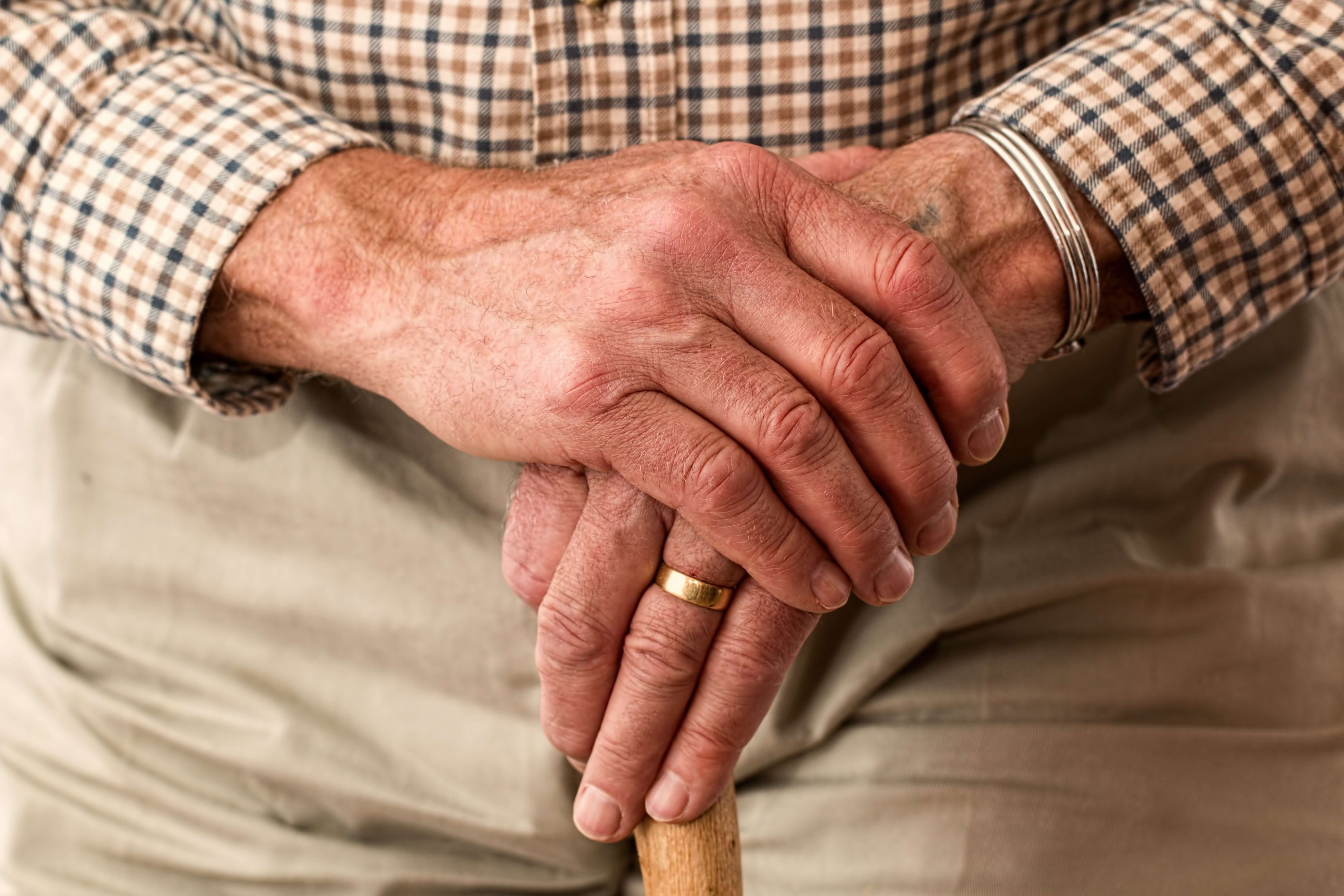 old person hands holding cane