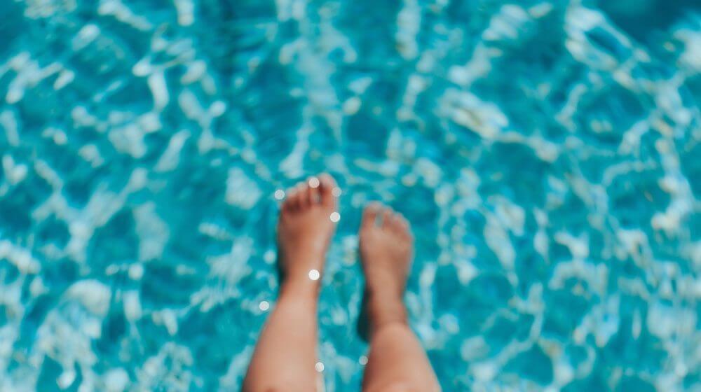person dipping their feet in a pool