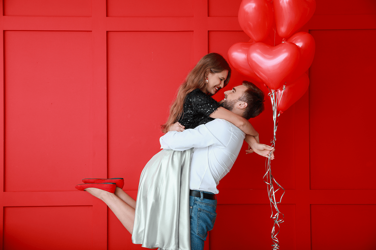 a couple hugging with red heart balloons